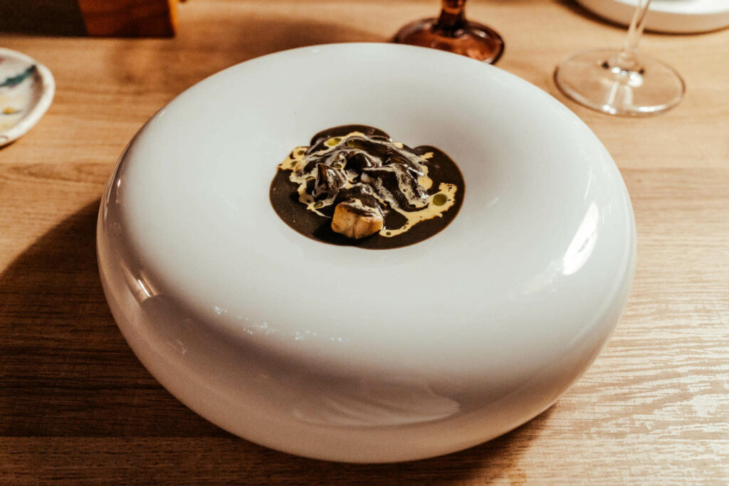 Auf einer hohen, flachen Schüssel wird das Essen vom 9 Gänge Menü im Tast Ller in Barcelona kunstvoll serviert.