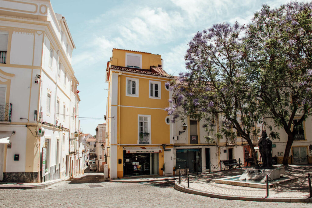 Ein blühender Jacaranda Baum vor einem gelb angestrichenen portugiesischen Gebäude im Elvas im Alentejo.