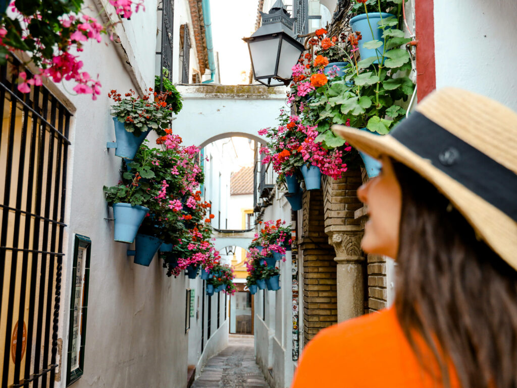 Durch eine kleine Gasse mit weißem Anstrich und Blumenkübel in Cordoba, Andalusien schlendert Reisebloggerin Nina von traveloptimizer. Córdoba ist ein echter Reiseziel Geheimtipp.