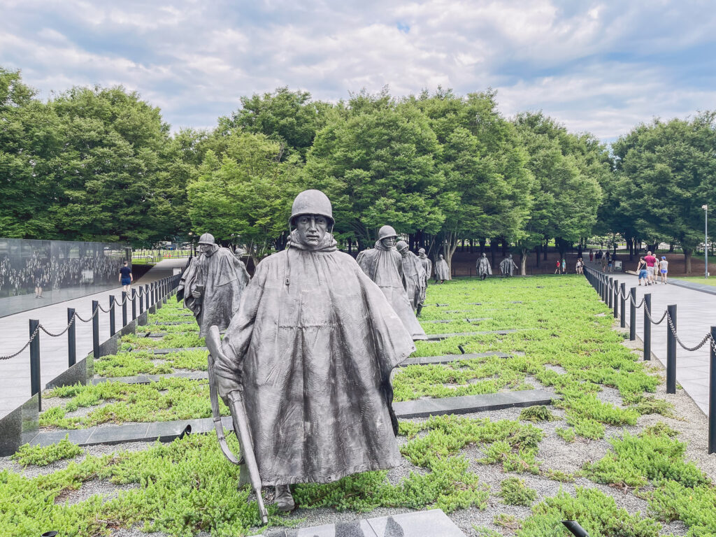 Ein großer Abschnitt einer Wiese mit prachtvollen Bäumen im Hintergrund bietet dem Korean War Memorial in Washington, D.C. seine geeignete Bühne.