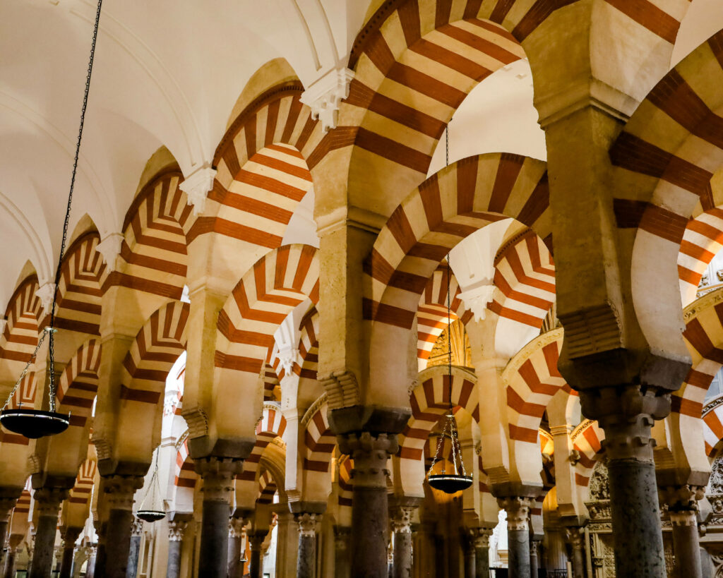 Beindruckende rot-weiß verzierte Rundbögen-Architektur findet man in Cordoba in der Mezquita.