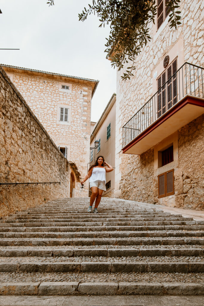 Ein aus Natursteinen geebneter Weg führt vorbei an breiten Balkonen eines mallorquinischen Dorfes.
