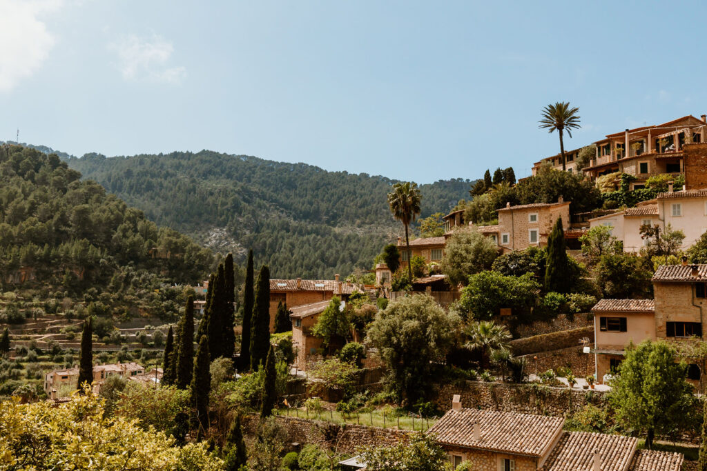 Mallorquinische Steinhäuser in Serra Tramuntana umgeben von einer grünen Berglandschaft.