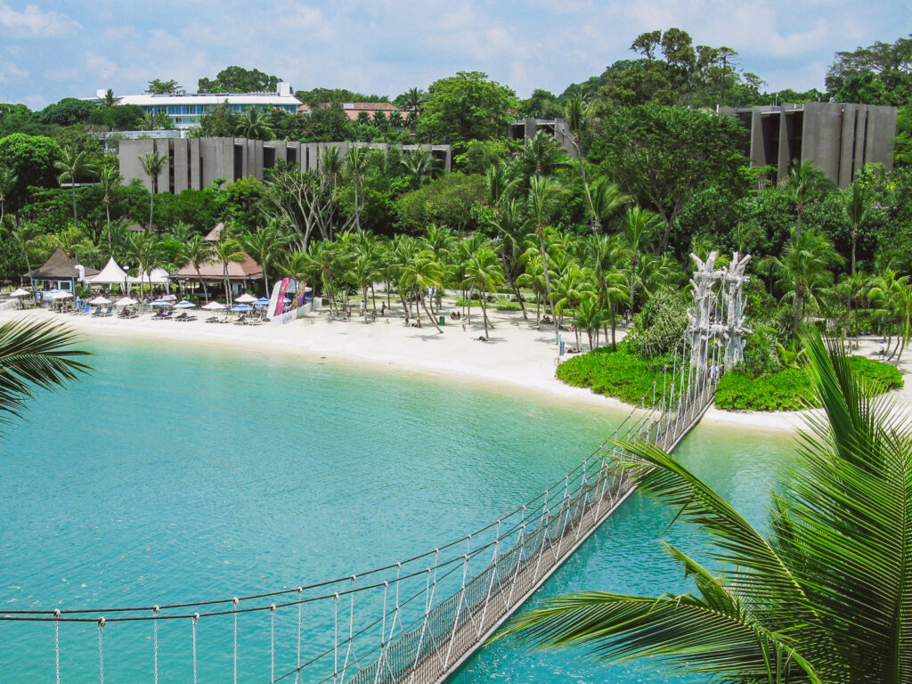 Türkis blaues Meer mit einem palmenbesetzem Sandstrand in Singapurs Oase Sentosa.
