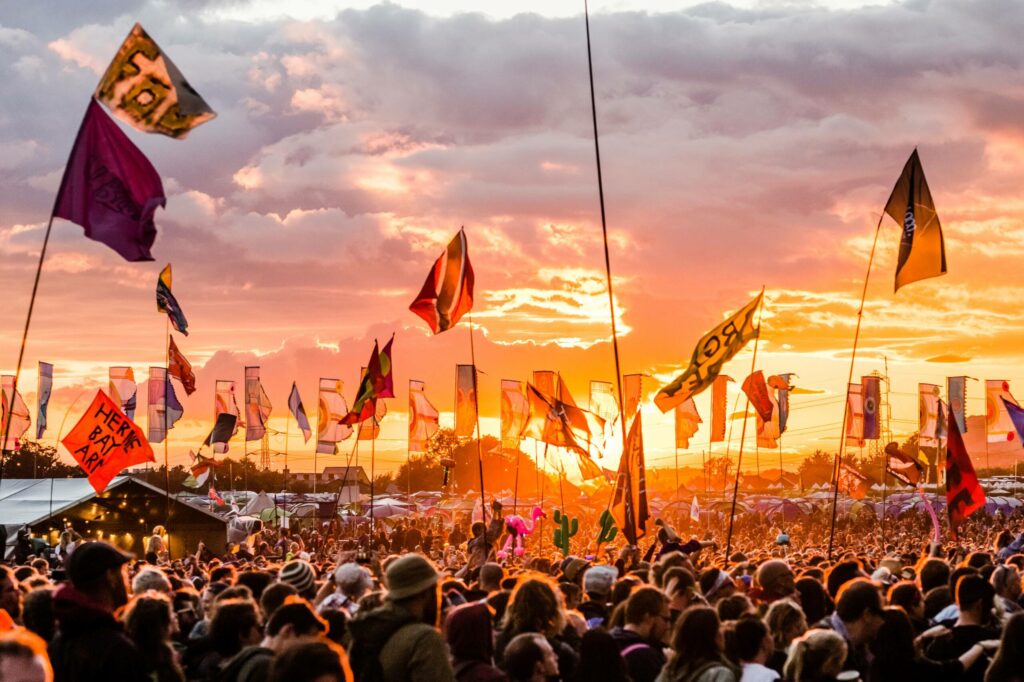 Fahnen, Ballons und Menschenmengen vorm Sonnenuntergang - das Glastonbury Festival in Bristol ist ein Highlight für jeden, der Musik Festivals liebt.