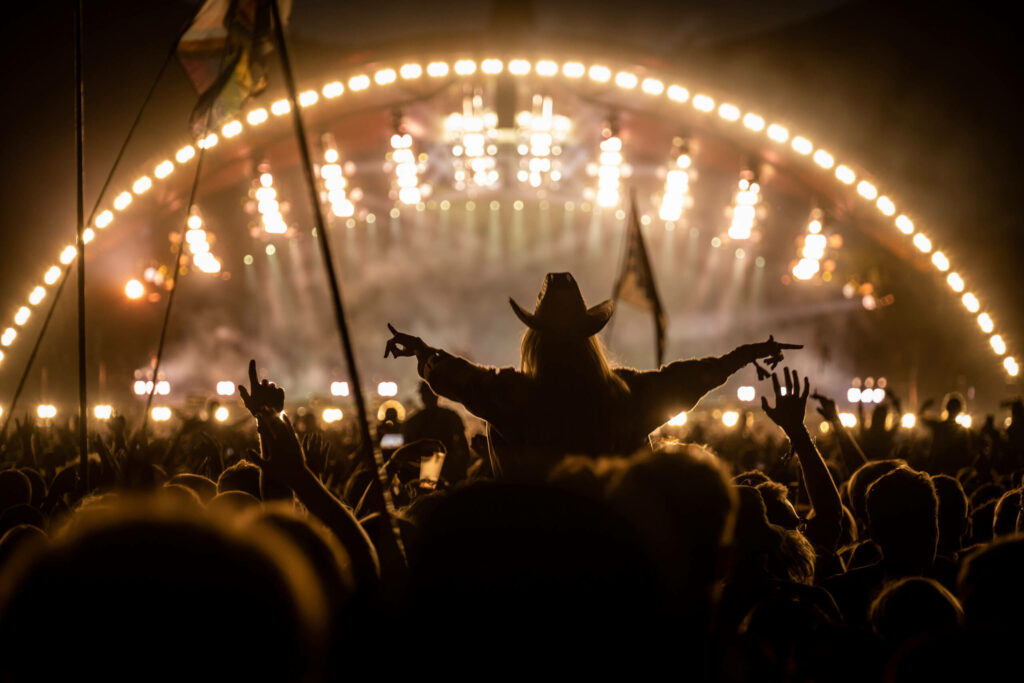 Mit Cowboyhut sticht eine tanzende Frau aus der Menschenmenge auf dem Roskilde Festival in Dänemark heraus.
