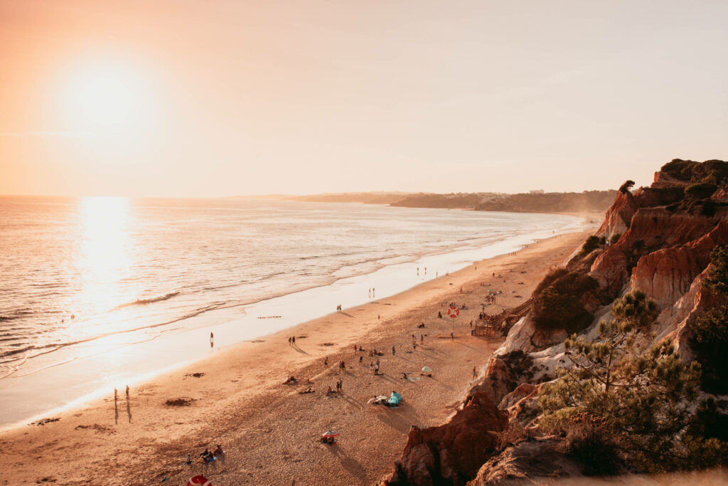 Der Strand der Praia da Falesia in Faro im Abendrot zwischen Meer und Felsen.