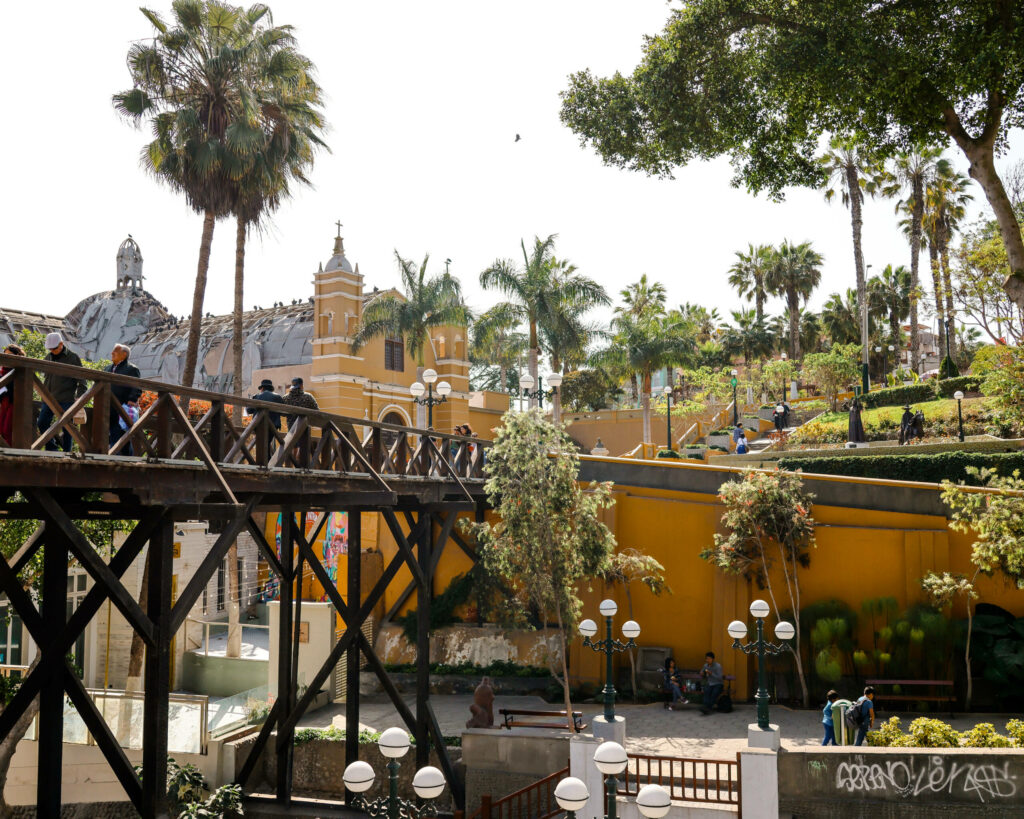 Zwischen Palmen ist die, aus dunklem Holz bestehende, Seufzerbrücke in Lima.