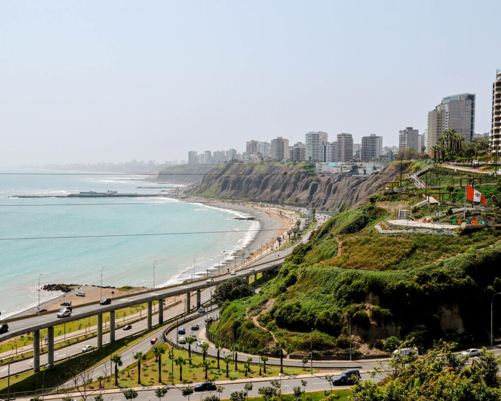 Eine lange Küste mit Strand, Straßen und begrünten Hügeln erstreckt sich in Lima.