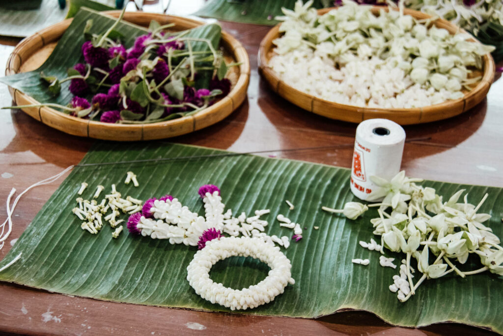 Auf einem Schilfblatt liegt andachtsvoll die Bastelarbeit mit weißen und rosafarbenen Blüten: Garlands sind in Thailand uralte Traditionskunst. und zählen damit zu einem Geheimtipp Bangkoks.