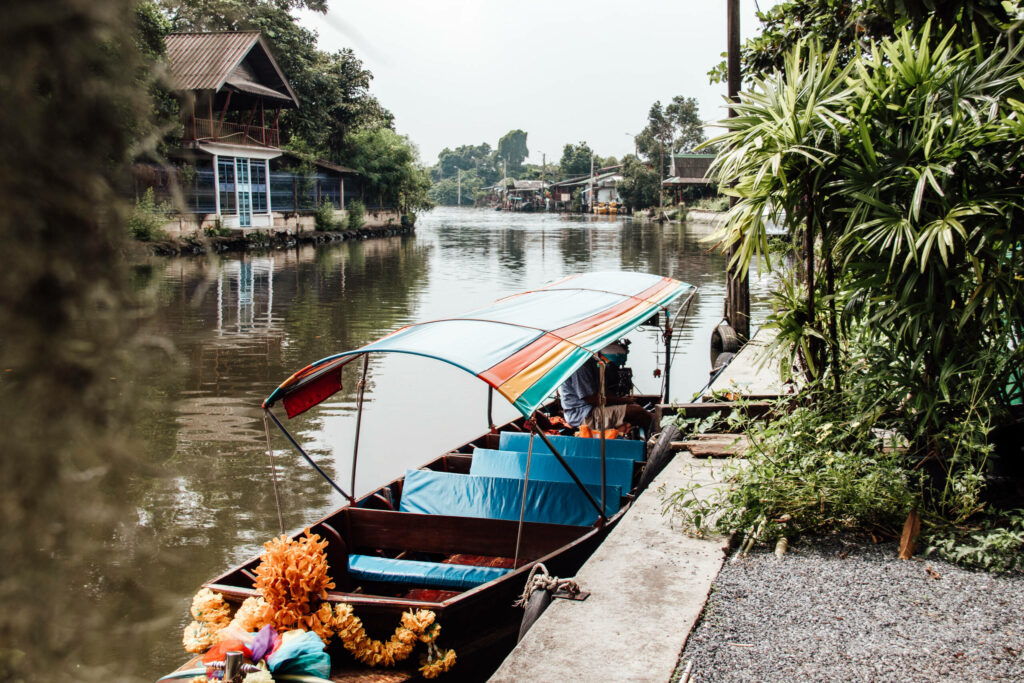 Ein Longtailboot mit bunter Plane liegt am Ufer des Flusses durch Bangkok.