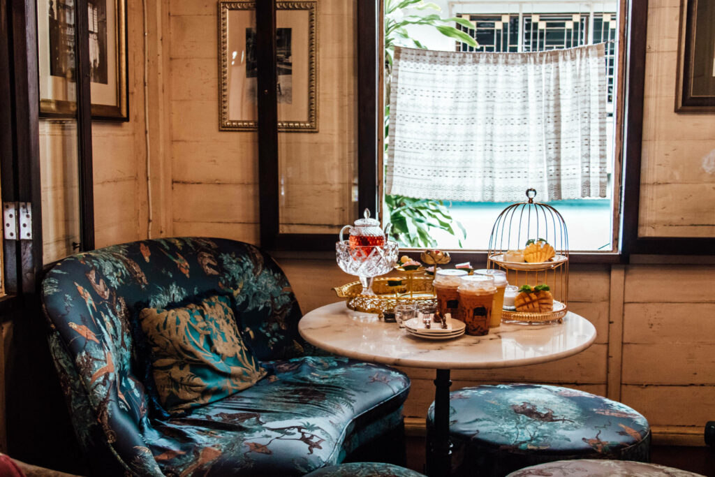 Ein Tisch im Gingerbread House auf dem thailändisch Teespezialitäten stehen umgeben von petrolfarbenen Couchmöbeln.