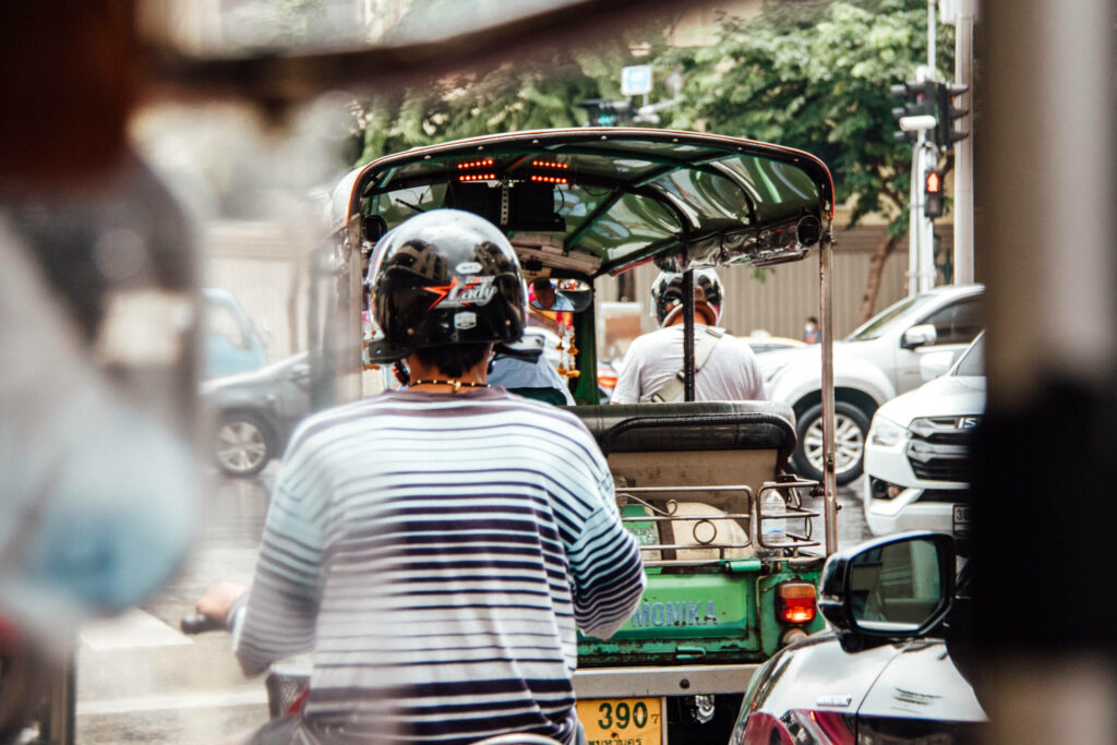 Tuk Tuks und Einheimische auf Rollern schlängeln sich durch Bangkoks Straßenverkehr.