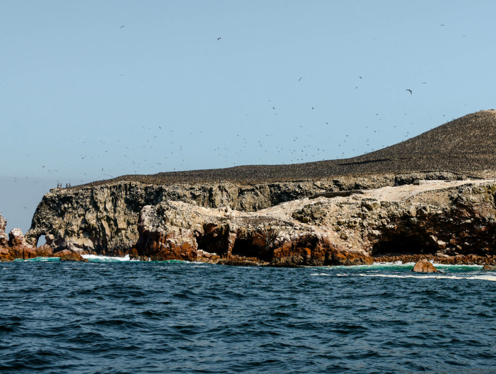 Das blaue Meer im Vordergrund einer felsigen Küste der Ballestas Islands in Lima.