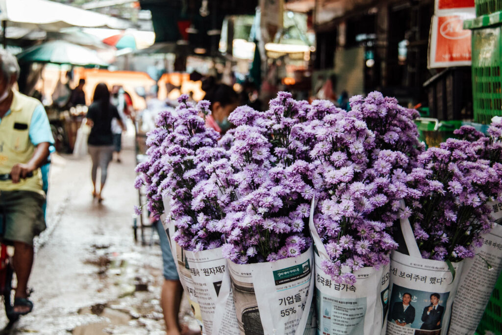 Lilafarbene Blumen in Zeitungspapier eingewickelt auf einem Markt in Bangkok.