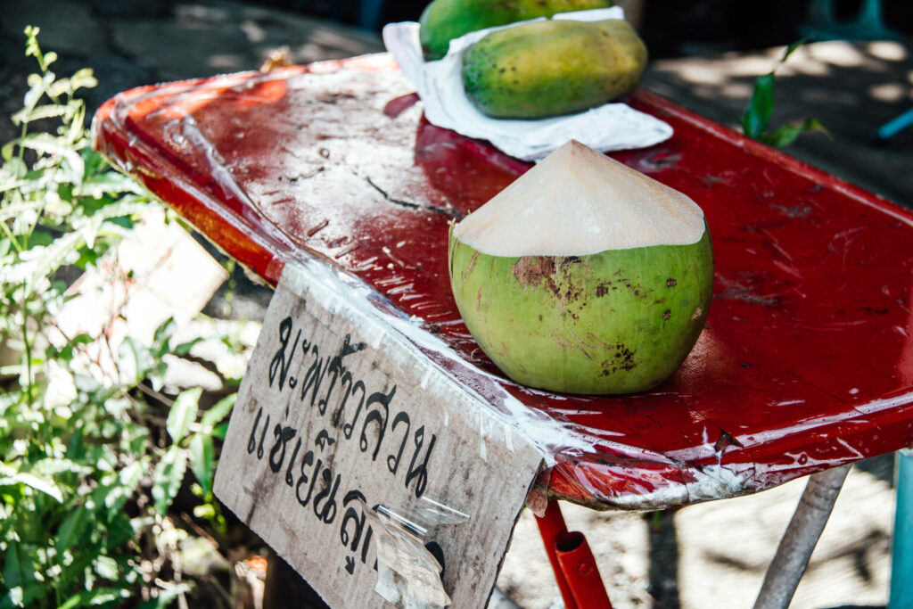 Eine frische Kokosnuss zum Mitnehmenauf einem roten Tisch.