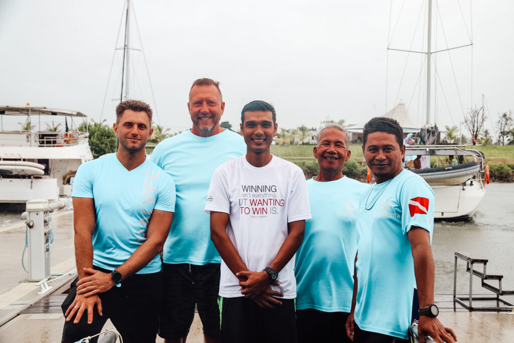 Fünf Männer aus dem Team von Fast Manta in Krabi mit Booten im Hintergrund.