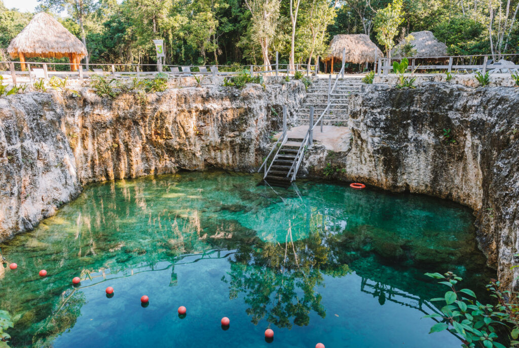 Die Cenote 7 Bocas auf Yucatan ist von türkisblauem Wasser und einer Felsmauer umgeben.