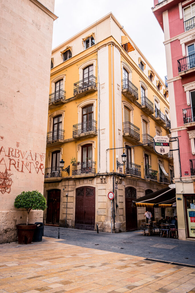 A yellow older house with balconies and wooden doors in Alicante.