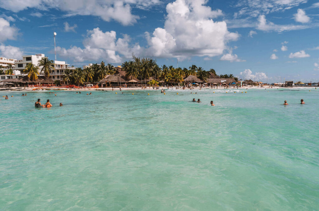 Menschen baden im türkisblauen Wasser am Playa Norte, einem Strand auf Yucatan.