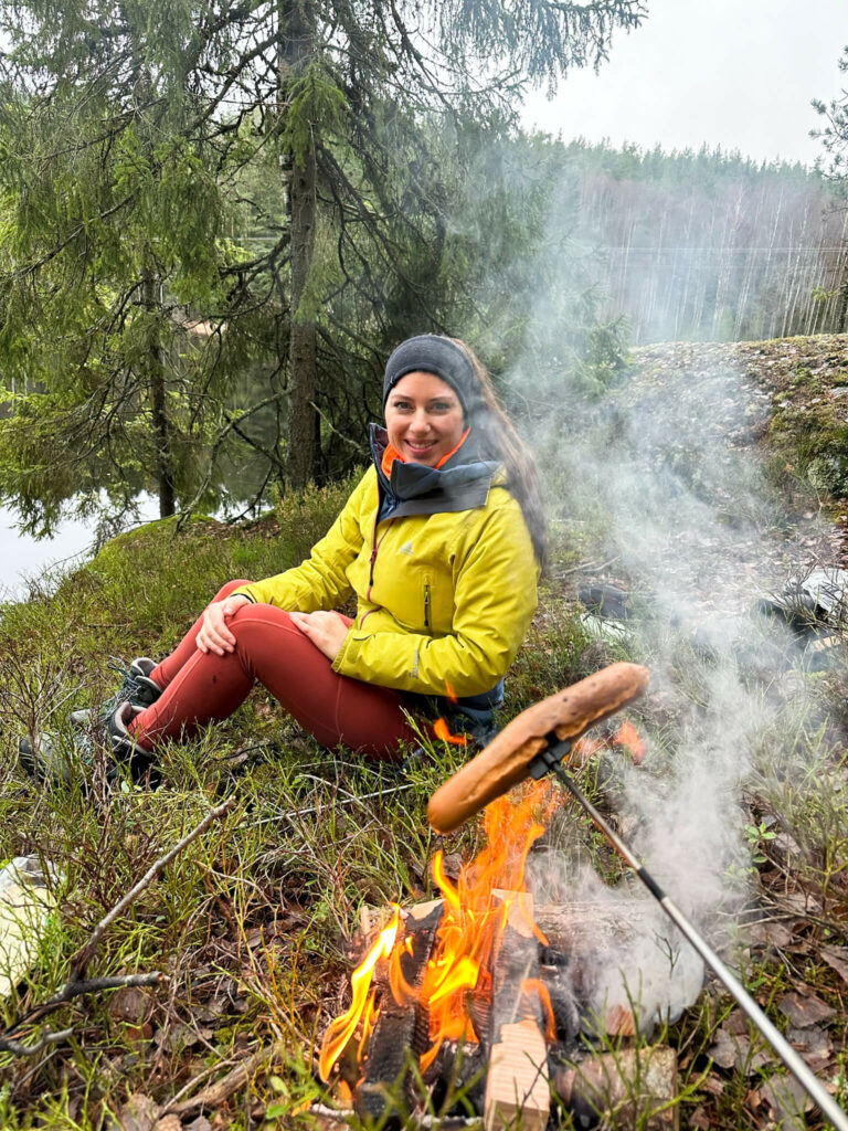 Bloggerin Biggi mit einer Bratwurst am Lagerfeuer im Wald von Oslo.