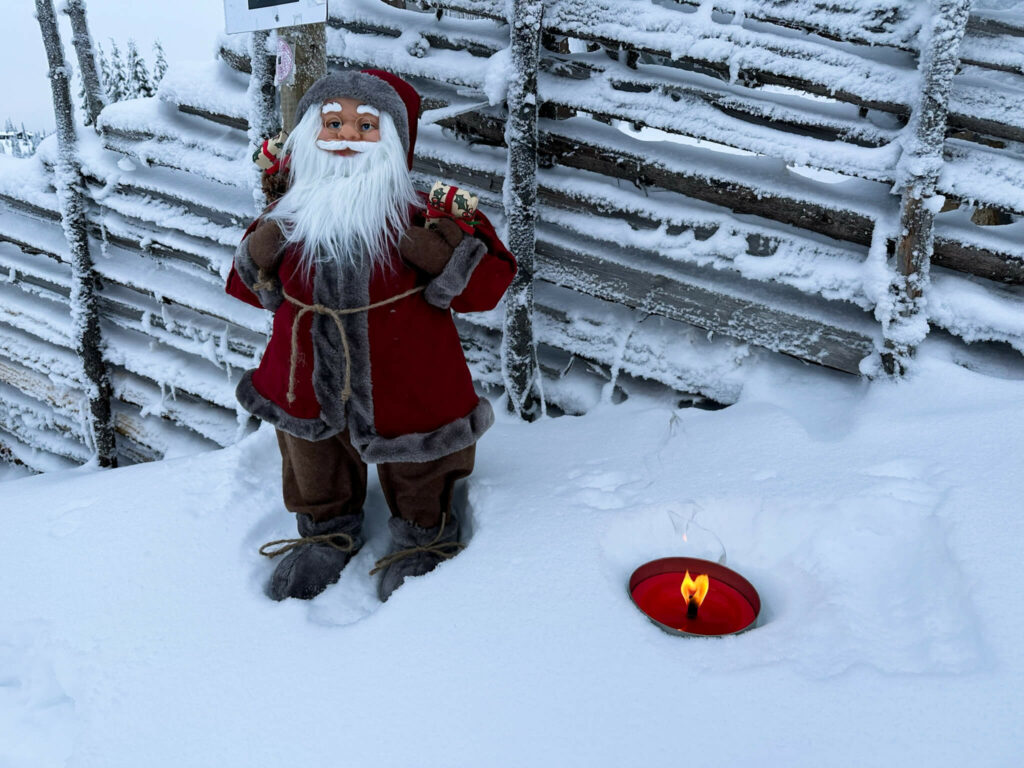 Eine kleine Weihnachtsmann-Figur im roten Mantel im Schnee.