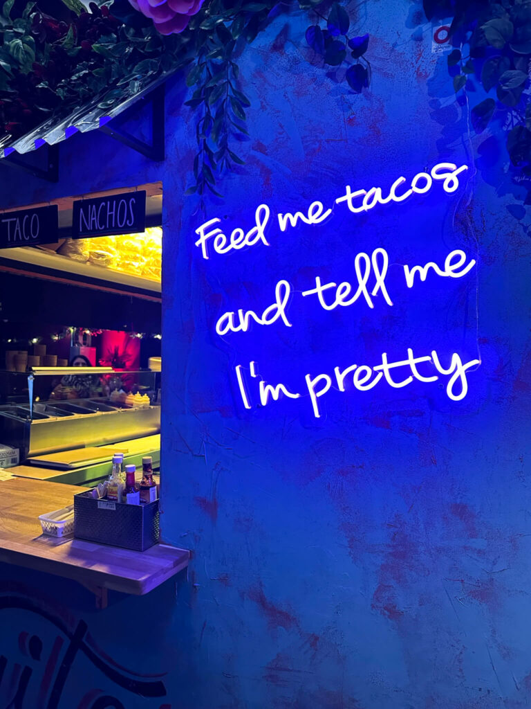 In blauer Leuchtschrift steht im Geheimtipp Street-Food-Laden Barcode in Oslo der Schriftzug "Feed me tacos and tell me I'm pretty".