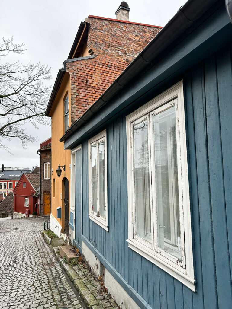 Ein blaues Holzhaus mit weißen Fensterrahmen ziert die Straße Damstredet in Oslo.