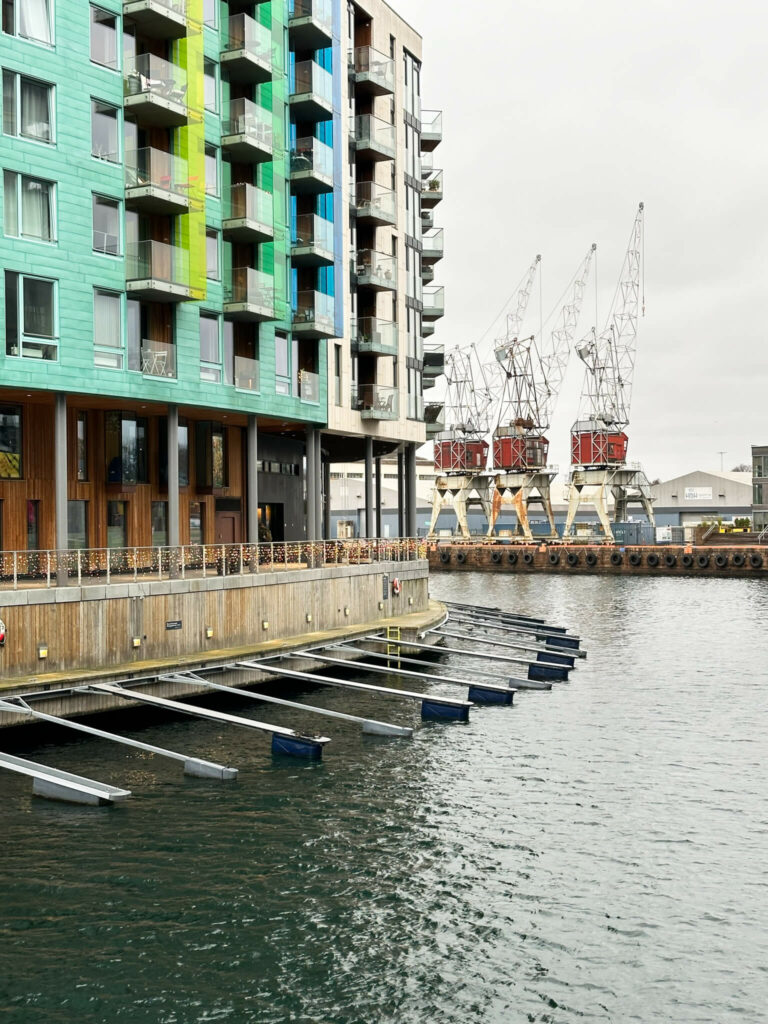 Ein moderner Neubau, direkt am Wasser, mit alten Hafenkränen im Hintergrund, ist ein Wahrzeichen der Halbinsel Tjuvholmen in Oslo.