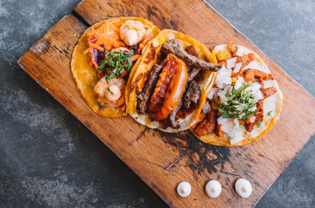 Tacos liegen angerichtet auf einem Holzbrett in der La Taqueria in Tulum auf Mexikos Halbinsel Yucatan.