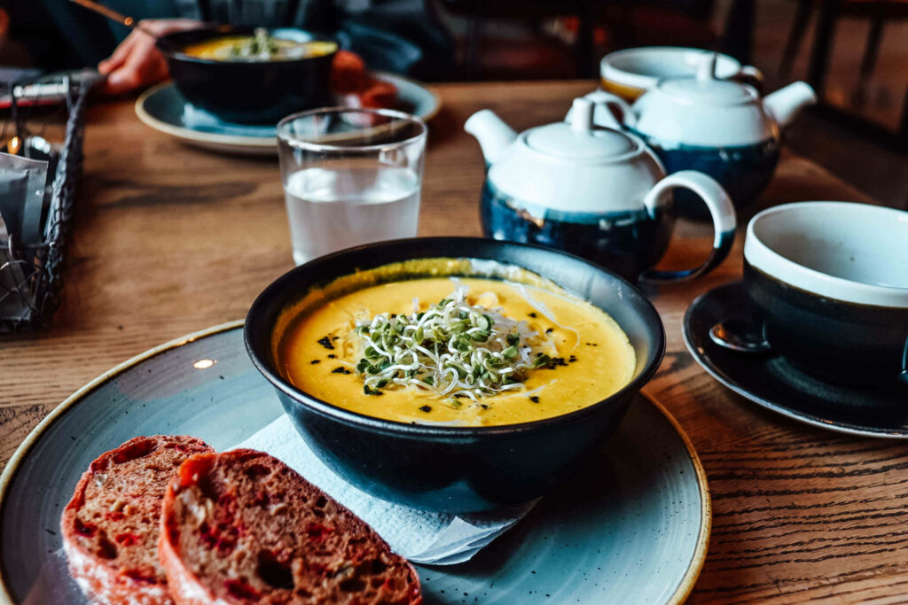 Eine gelbliche Suppe in einer Schüssel, dazu Brot auf einem Teller im Grey Restaurant in Vilnius.