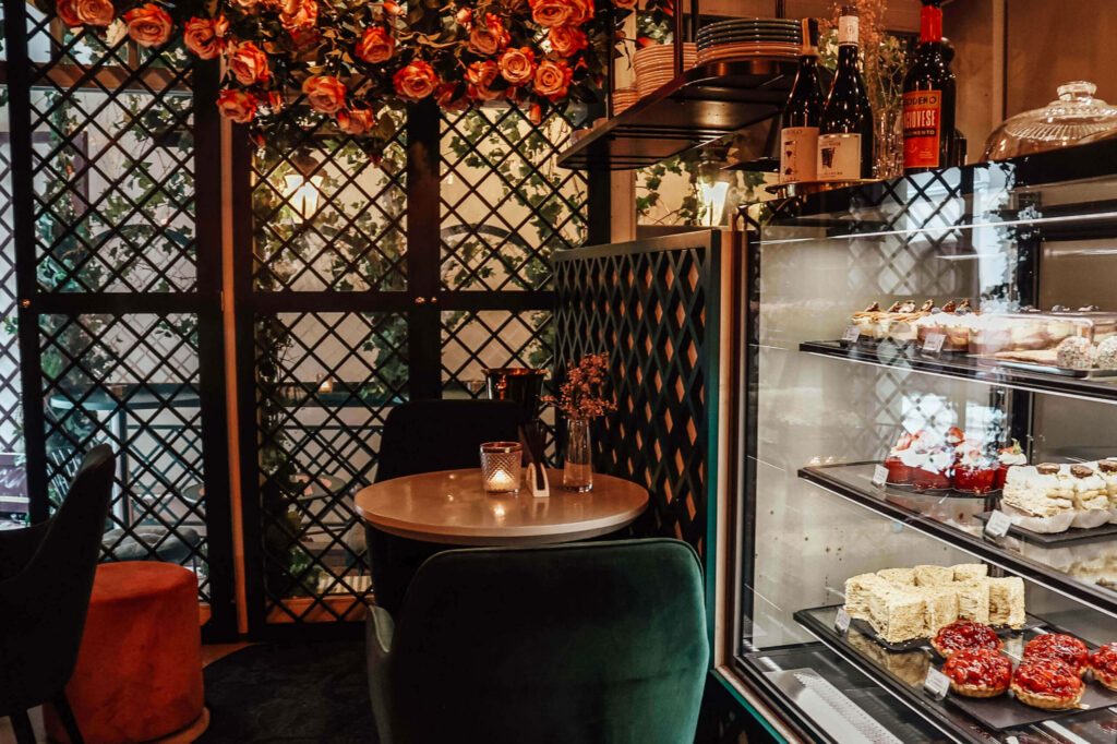 Ein Tisch mit grünen Samtstühlen am Kuchenbuffet des Augustas Barbora Cafes in Vilnius.
