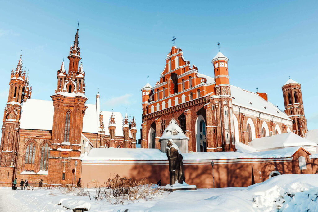 Die backsteinfarbene Kirche St. Anna in Vilnius im Winter mit Schnee bedeckt.