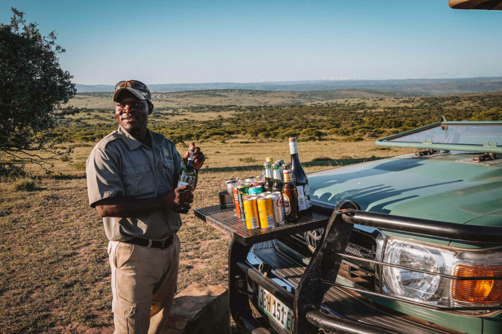 Ein Guide richtet Getränke vor seinem Auto an im Game Reserve in Südafrika.
