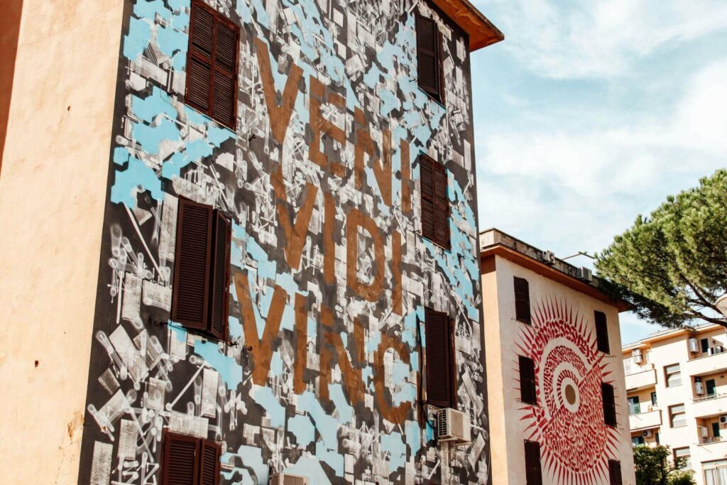 Ein Street-Art-Spot in Rom - ein Hauswand mit braunem Schriftzug.