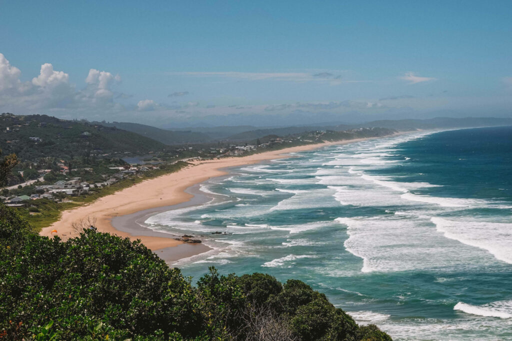 Blick vom Dolphin Point auf den Strand und das türkisblaue Meer in Wilderness in Südafrika.