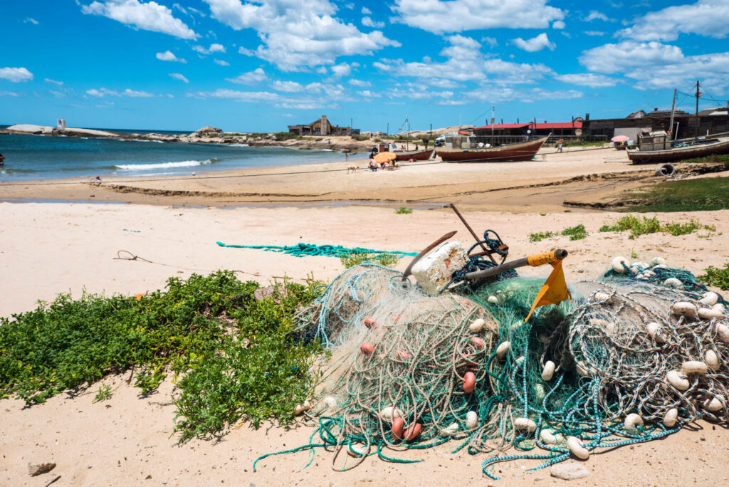 Im Fischerdörfchen Punta del Diablo in Uruguay liegen kleine Boote und Fischernetze am Strand.