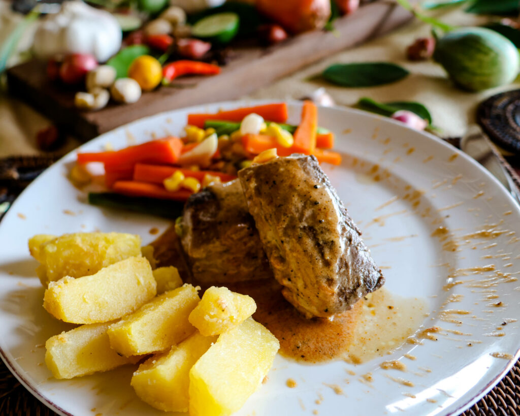 Ein Teller mit Kartoffeln, Fleisch und Gemüse aus dem Katembe Private Island Resort auf Raja Ampat.