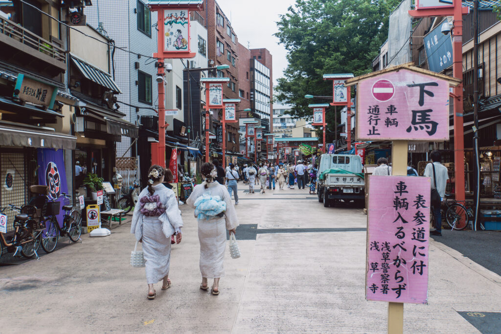Frauen in Kleid ähnlichen Gewändern schlendern durch eine Straße in Tokio.