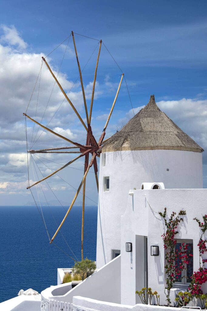 Eine weiße alte Windmühle mit Blick aufs blaue Meer in Griechenland.