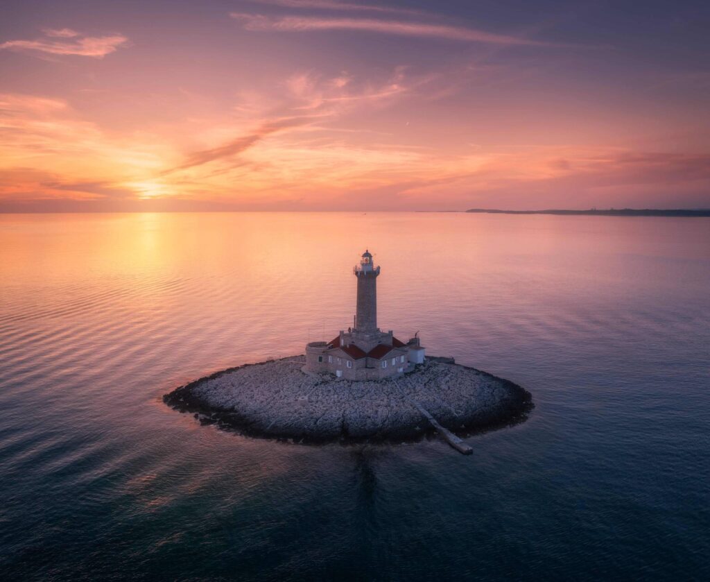 Ein alter Leuchtturm auf einer kleinen Insel in der Adria bei Pula bei Sonnenuntergang.