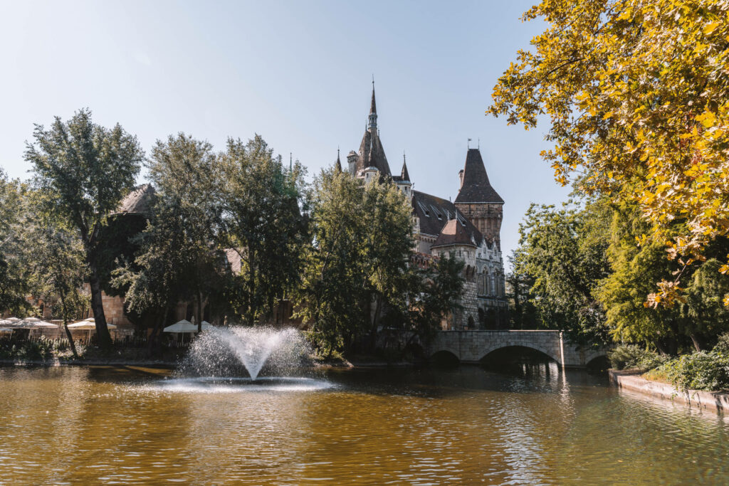 Die alte Burg Vajdahunyad in Budapest versteckt sich hinter einem See und Bäumen.