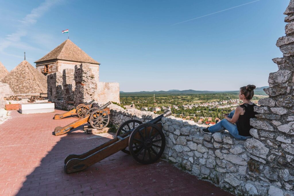Bloggerin Melanie sitzt auf der Steinmauer der Burg Suemeg in Ungarn und schaut in die Ferne.