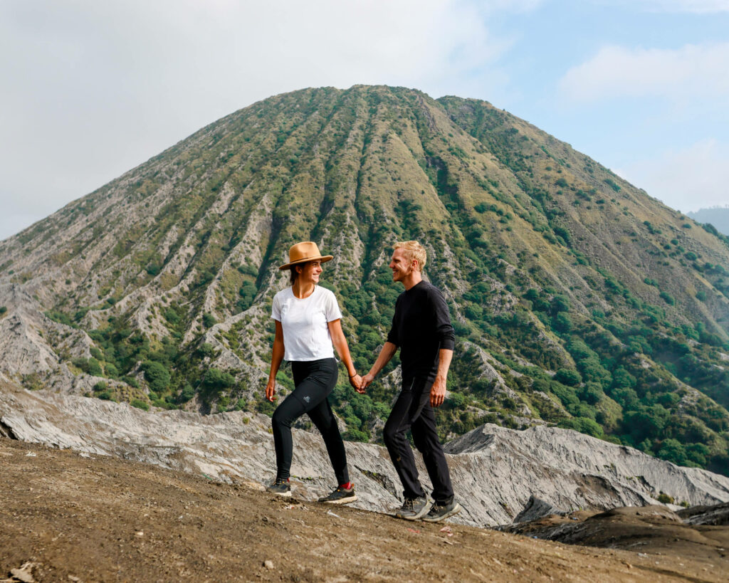Die Blogger Nina und Tom spazieren Hand in Hand am Vulkan Bromo in Java.