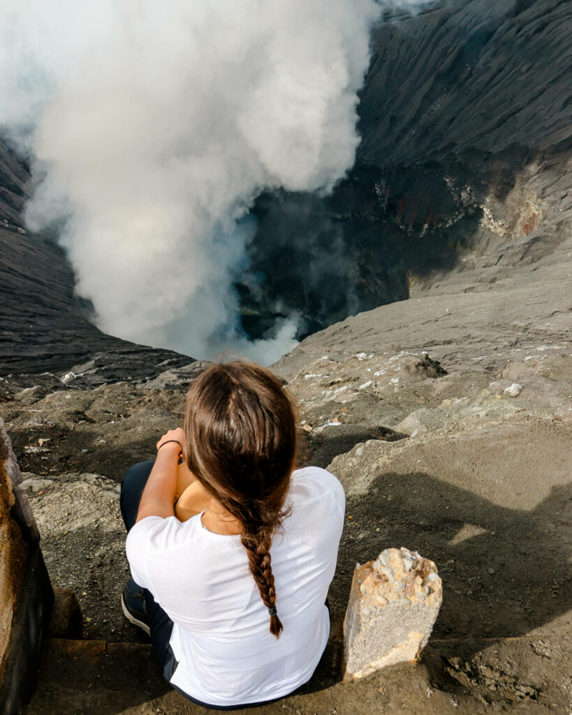 Bloggerin Nina sitzt am Kraterrand des Vulkans Bromo in Java.
