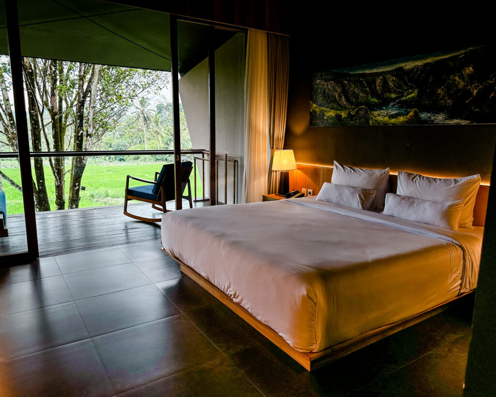 Ein Hotelzimmer in Java in der Nähe des Mount Ijen mit großem Bett und Blick auf den Balkon.