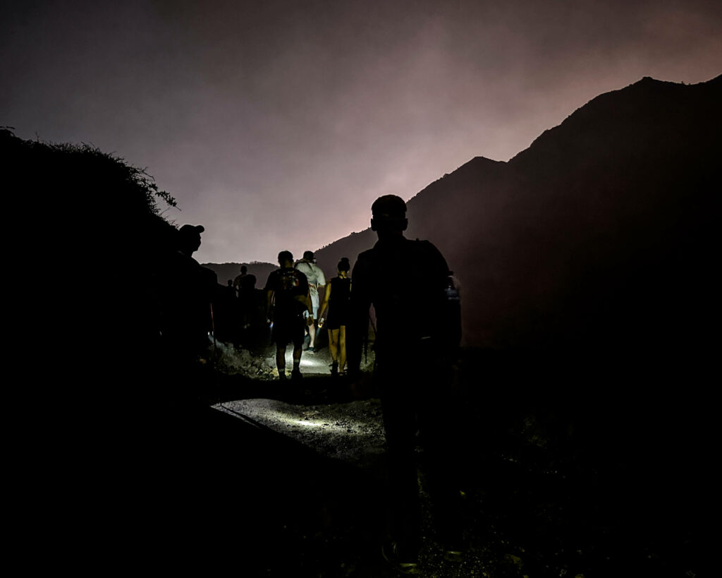 Menschen wanndern in der Nacht auf einem Weg mit kleinen Lampen in Java.