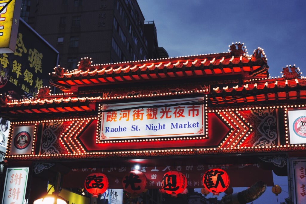 Ein rot beleuchtetes Tor führt zum Raohe Nachtmarkt in Taipeh.