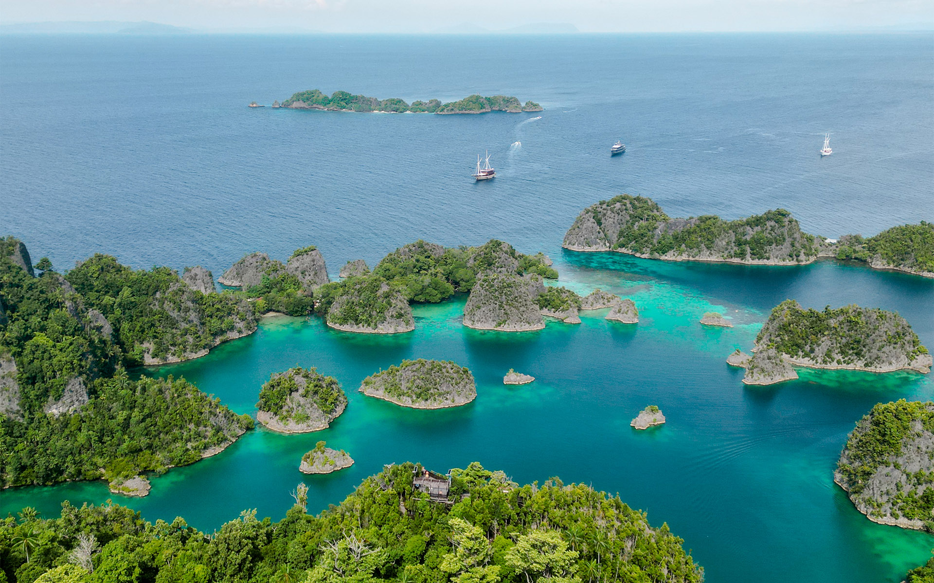 Kleine steinerne Inseln umgeben von türkisblauem Meer bei Piaynemo Island auf Raja Ampat.
