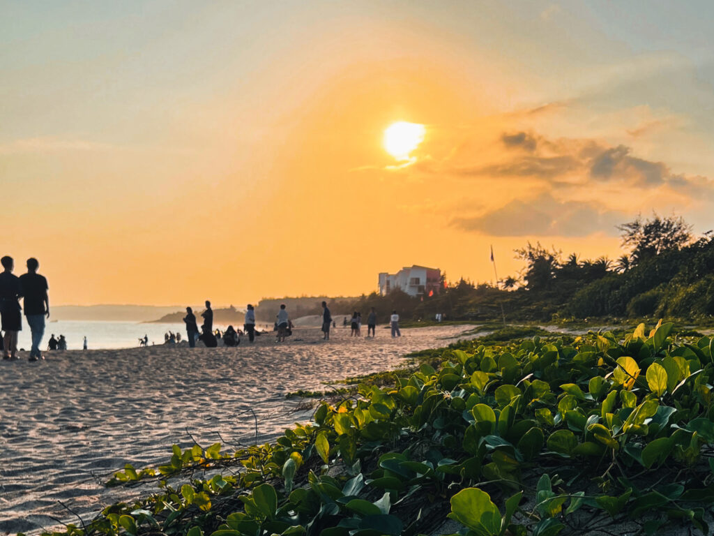Menschen schauen sich den Sonnenuntergag am Strand des Dawan Beach in Taiwan an.